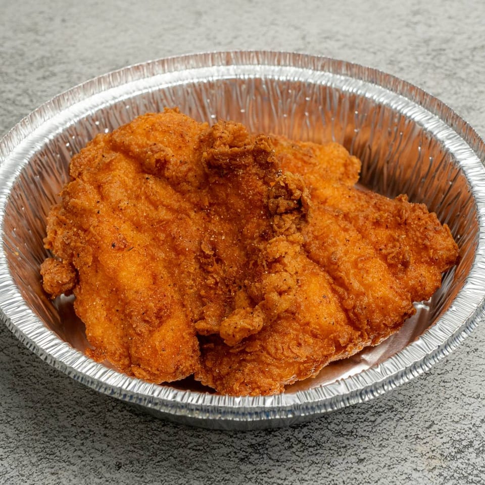 Golden-brown fried chicken pieces in a round, silver foil takeout container from Angie's Soul House.
