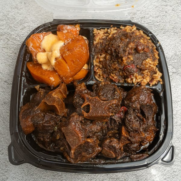 Angie's Soul House oxtail, rice, and candied yams in a black takeout container.