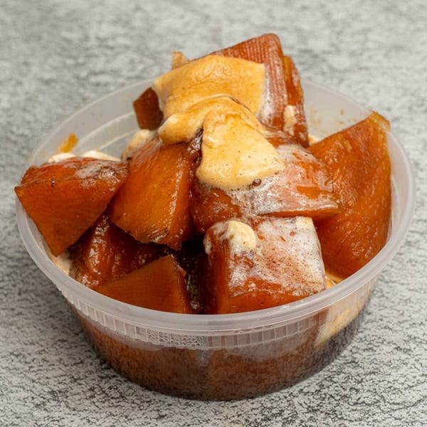 Angie's Soul House candied yams, glistening with syrup and topped with melted marshmallows in a plastic container.