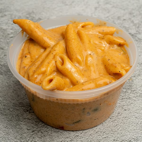 Angie's Soul House penne pasta in a creamy orange sauce with black pepper in a plastic container.
