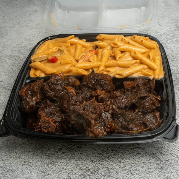 Angie's Soul House oxtail and creamy penne pasta in a black takeout container.